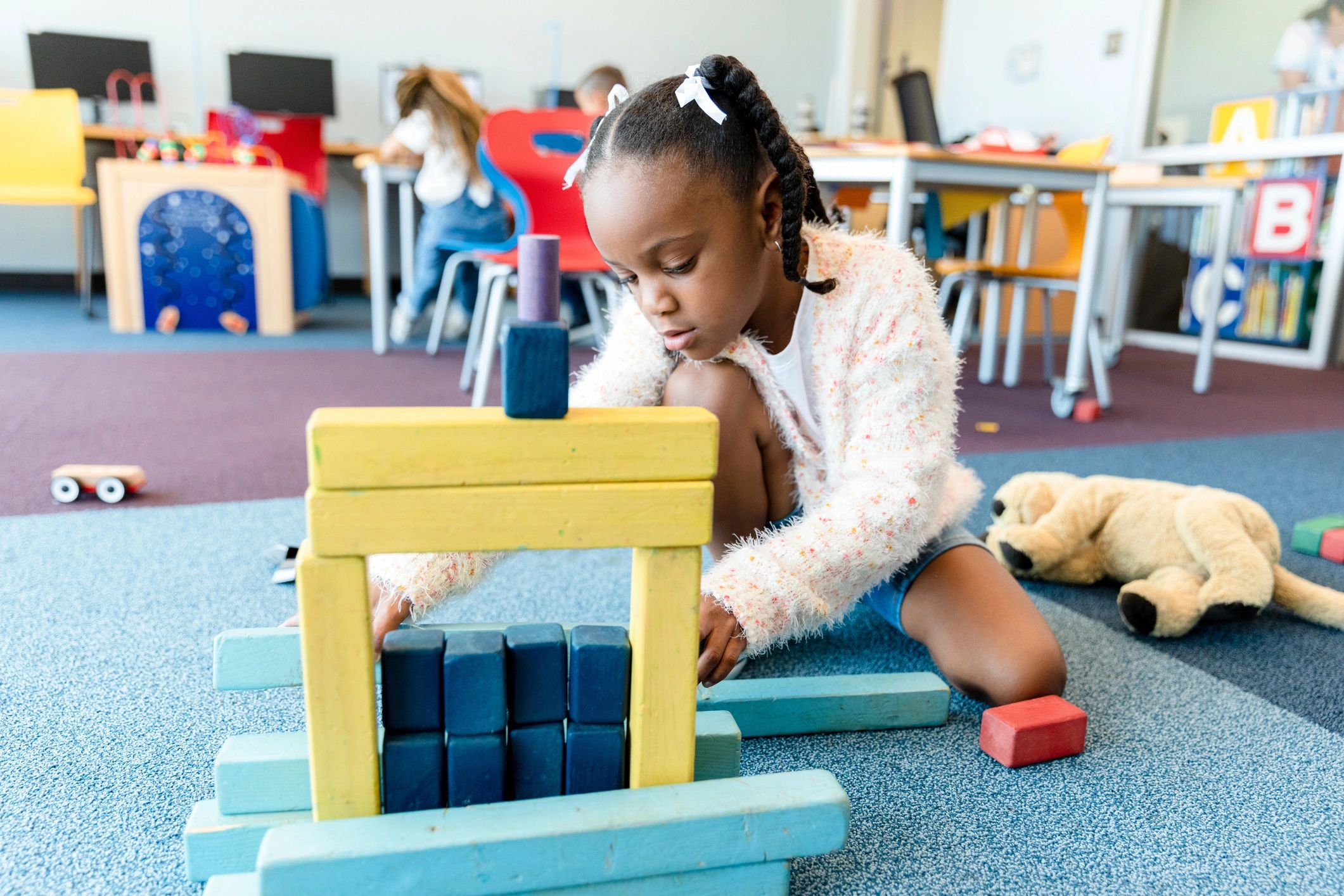 Child playing with wooden blocks on the classroom floor