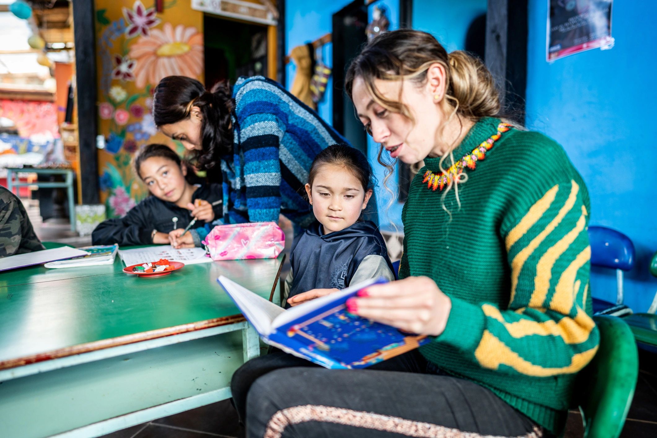 Teacher reading a book with a child in a classroom