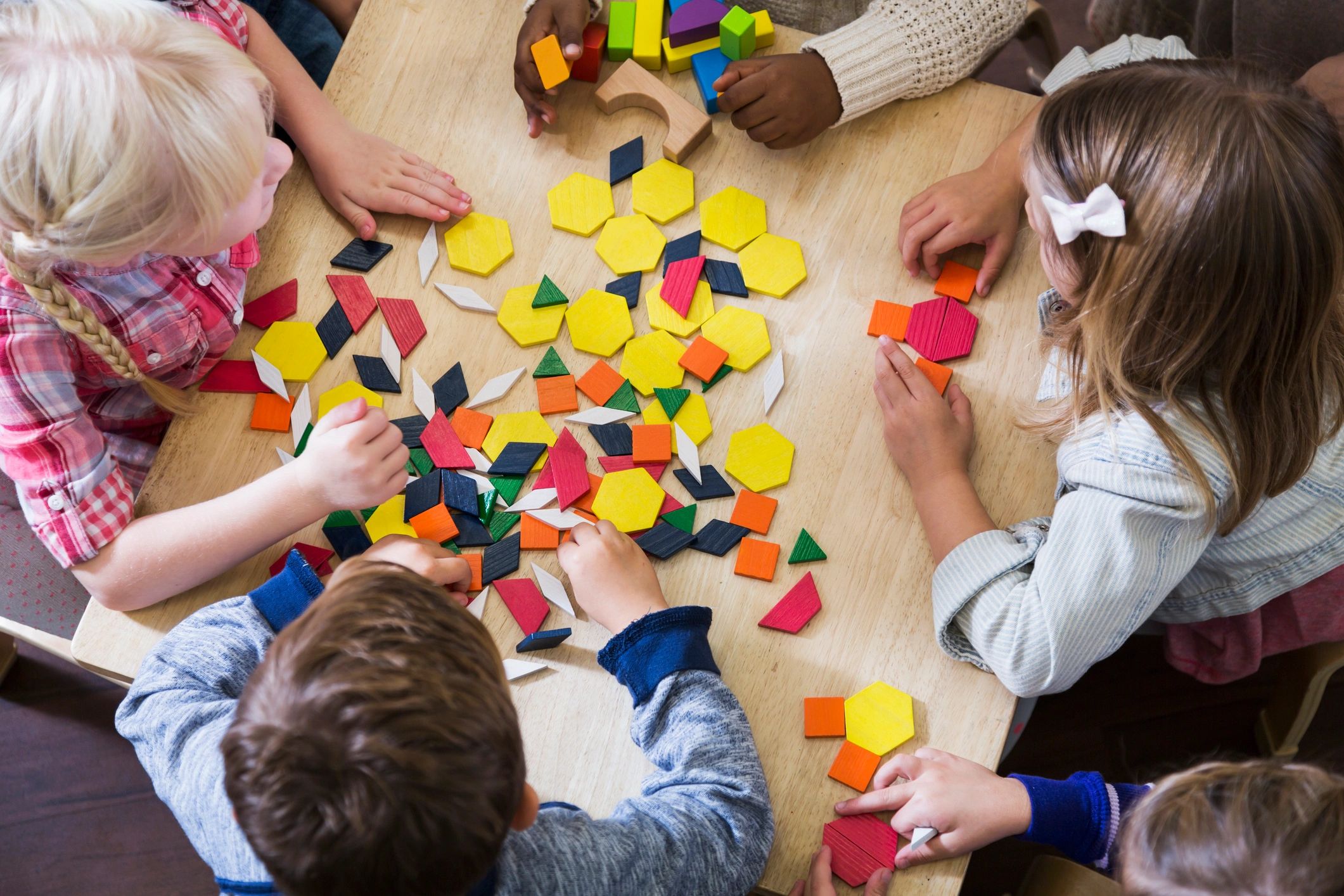 Children playing with colorful blocks and shapes at a classroom table